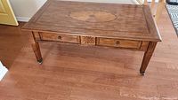 Full front view of the rectangular wood coffee table with 2 drawers and casters.