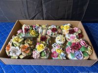 Box with twelve antique bone china flower figurines in various colors on white bases.