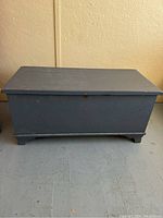 Closed rectangular cedar chest with blue painted exterior showing surface wear and scratches.