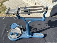 Full view of the blue metal Fisher Scientific triple beam balance with pan, scale arms and weights.