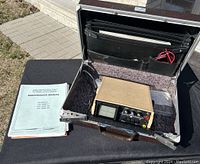 Huntron Tracker device inside open Samsonite case with maintenance manual beside it.