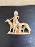 Front view of beige figurine showing the lady with her two dogs.