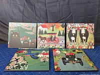 All five prints arranged on a blue padded surface against a dark backdrop