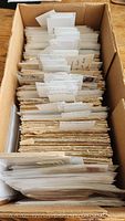 Photo of a box filled with numerous vintage envelopes organized with tabs for the collection of postmark slogan stamps.