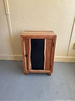 Front view of solid cherry nightstand showing door with natural wood frame and black central panel.