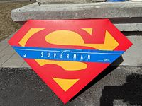 Diamond-shaped red box featuring large yellow Superman 'S' logo with blue sleeve that reads 'Superman' and logos for Warner Bros and other trademarks.