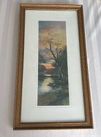 Full front view of framed vertical painting showing the tree by lake at sunset with gold frame and cream matting