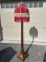 Full view of floor lamp showing red fabric shade, wooden column and square base