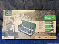 Original box showing Woods Quick Fire Propane Stove branding, 20,000 BTU output, and product features.