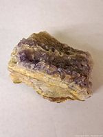 Photo showing the rough crystalline surface of amethyst with purple hues and yellowish mineral base.