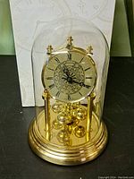 Front view of the vintage Bulova mantle clock inside a glass dome on a gold-tone base.