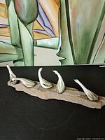 Wide angle photo showing the entire ceramic sculpture with four geese on a wooden base against an artistic green background.