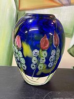 Front view of the vase showing pink tulip-like flowers and white clusters on blue background with yellow highlights.