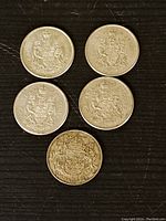 Top view of all five Canadian 50 cent silver coins with coat of arms design visible.