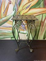 Front view of the metal planter stand showing woven lattice top and ornate curled legs.