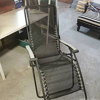 Full view of reclining lawn lounger showing black mesh fabric and metal frame.