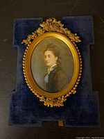 Front view of the small antique framed oval portrait showing the detailed gold frame and the painted lady.