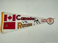 Full front view of the pennant showing Canada and Soviet Union flags, 'Canada vs. Russia 1972' text, hockey player graphic, and promotional logo.