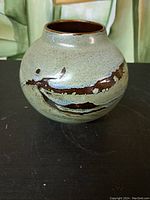 Front side view of the ceramic vase showing the rounded shape and distinctive glaze pattern with green and brown colors.