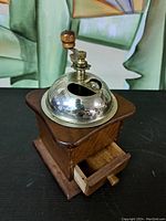 Side angle of vintage wooden coffee grinder with silver metal dome and wooden drawer pulled out slightly