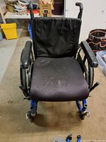 Front view of blue metal frame wheelchair showing seat cushion and armrests