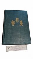 Blue cloth hardcover book with gold embossed illustrations on front cover representing characters from The Wind in the Willows.