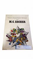 Front cover of the book featuring the geometric star shape with colorful figures representing M.C. Escher's art style. The book is titled 'The Graphic Work of M.C. Escher'.