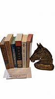 Side view showing thickness and condition of the books along with the brass horse head bookend.