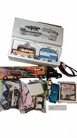 Top view showing boxed ceramic car and trailer in styrofoam packaging, large toy truck, and various plastic models in bags with Ryder sunglasses