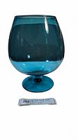 Full view of large blue glass footed vase with smooth translucent surface and rounded shape.