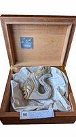 Soapstone eagle sculpture nestled inside an open wooden box with cloth lining and a label visible inside the lid.