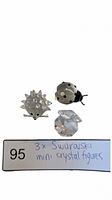Three Swarovski crystal mini figurines: hedgehog, ladybug, and clam with pearl, arranged for lot display