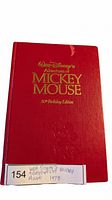 Front cover of the red hardcover book featuring gold embossed text and an embossed Mickey Mouse image.