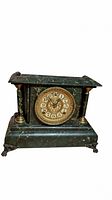 Front view of vintage mantle clock showing green marble finish, ornate gold clock face, Roman numerals, decorative columns, and claw feet.
