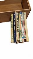 Ten vintage romance novels standing side by side in a wooden box, visible titles and spines show wear and age.