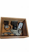 Wooden box containing assorted vintage items: Timex watch with brown leather strap, eyeglasses with black frames, two black ring holders, small metal tin labeled 'Slips'.