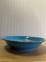 Side profile photo showing the turquoise ceramic bowl with decorative multi-color rim.