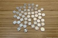 33 uncirculated 2001 U.S. State Quarters spread out on a wooden surface showing obverse sides mostly.
