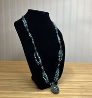Full view of aquamarine beaded necklace displayed on black mannequin bust, showing length and pendant.