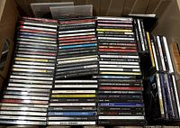 Photo showing stacked jewel case CDs, various artists and genres visible.