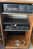 Wooden cabinet with Onkyo receiver on top shelf, Pioneer CD player on middle shelf, and cables on bottom shelf.