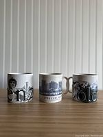 Front view of three Starbucks city-themed coffee mugs on a wooden surface against a white vertical paneled background