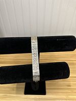 Front view of the vintage hand carved bracelet displayed on black velvet holder, showing the designs on the segments.