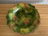 Top view of green porcelain leaf-shaped platter with detailed veins and orange accents.