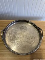 Top view of the round vintage silver plated serving platter with engraved floral patterns on the surface.