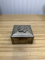 Closed view of the square silver plated presentation box showing the floral decoration on the lid.