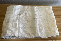 Folded vintage white lace tablecloth showing embroidered and lace panel design