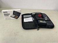 Photo showing the automotive wire finder kit inside a zippered black case alongside the digital scale box, placed on a white table.