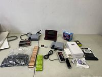 Overview of lot on table including 2 game systems, 3 controllers, Nintendo 3DS XL, batteries, power bank, earphones, and games.