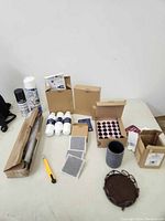 Top-down view of the lot items including boxes, spray cans, white filters, yellow utility knife, gray container, metal trivet, and small mesh filters.